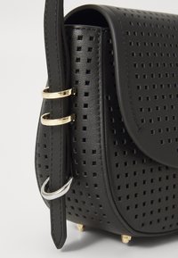 Borsa in pelle nera perforata con chiusura a pattina, caratterizzata da accenti di hardware dorato e argentato e una tracolla texture.