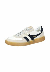 Licht beige sneaker met zwarte strepen, witte mesh panelen en een gumrubberen zool. Bevat platte veters met een gebogen patroon en logodetail.
