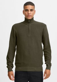 Olivgrüner Strickpullover mit hohem Kragen und halbem Reißverschluss. Verfügt über ein strukturiertes Muster sowie gerippte Bündchen und Saum.