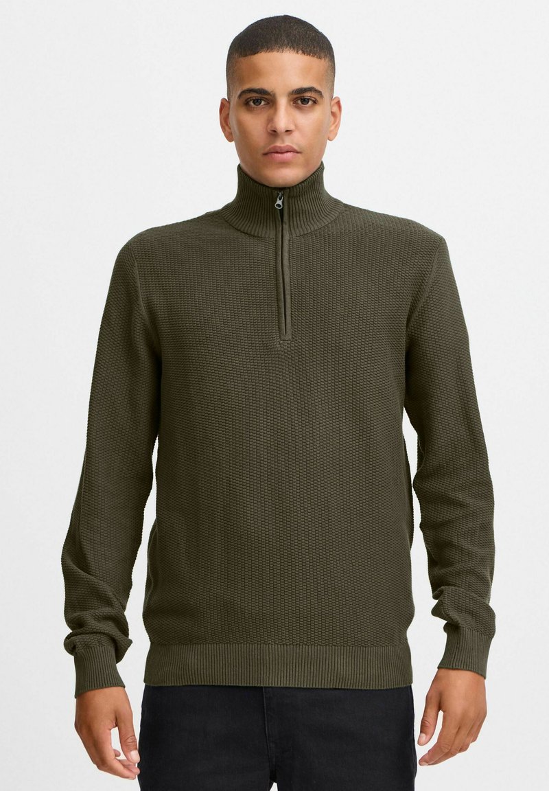 Olivgrüner Strickpullover mit hohem Kragen und halbem Reißverschluss. Verfügt über ein strukturiertes Muster sowie gerippte Bündchen und Saum.
