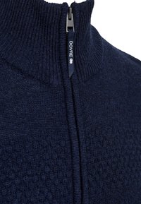 Navy blue zip-up sweater with a textured knit pattern and high collar. Features a black zipper with a "DOVRE" pull tab.