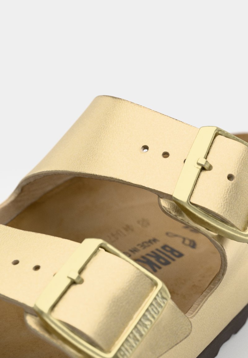 Goldene Leder-Sandale mit zwei verstellbaren Riemen und metallischen Schnallen, einer konturierten Fußbett und einer strukturierten Sohle.