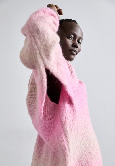 Maglione in maglia oversize con toni di rosa sfumati, realizzato in un tessuto morbido e texture, con spalle scoperte che mettono in risalto una silhouette rilassata.