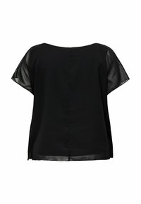 Sort top med en ensartet hovedstof og gennemsigtige ærmer. Den har en rund halsudskæring, løs pasform og slidser i siderne for ekstra detalje.