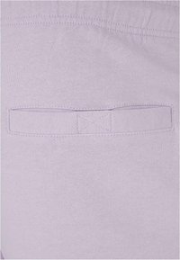 Light lavender fabric showcases a pocket with a stitched tab detail. The material is soft with a smooth texture and even stitching throughout.