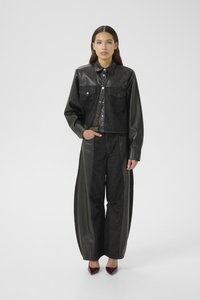 Black denim jacket with leather sleeves, cropped design, two chest pockets. Paired with wide black trousers featuring leather side panels.