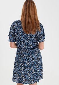 Kwiatowa sukienka z krótkimi, falbaniastymi rękawami, dopasowanym talią i granatowym tłem ozdobionym małymi niebieskimi, białymi i zielonymi wzorami kwiatowymi.