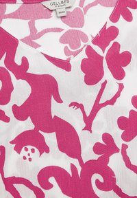 Bloemtop met een witte achtergrond en gedurfde roze abstracte bloempatronen, V-hals ontwerp en een lichtgewicht stoftextuur.
