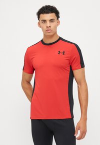 Rød sports T-skjorte med svarte sidepaneler, korte ermer og rund hals. Har Under Armour-logo på brystet. Materialet virker lett.