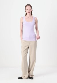 Lila tanktop met een ronde hals, gecombineerd met beige wijde broek. De stof lijkt zacht met een gladde textuur en een casual pasvorm.