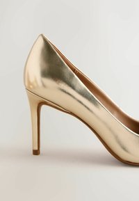 Zelta metāla augstpapēžu kurpes ar vērstu purngalu, gludu virsmu un slaidu stiletto papēdi. Gluda tekstūra un minimālistisks dizains.