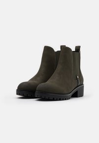 Botas de tobillo de ante verde oliva con suela de goma negra, paneles laterales elásticos y una tira en la parte trasera para ponerlas fácilmente. Diseño de tacón ancho.