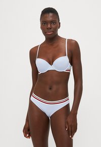 Šviesiai mėlynas bikinis su paminkštintu liemenėliu ir suderintais apatiniais, abu akcentuoti daugiaspalve raišteliu juosmens pusėje. Lygus paviršius.