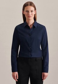 Marineblaues, langärmeliges Hemd mit Knopfleiste und Kragen, mit einer körperbetonten Passform und glatter Textur. Kombiniert mit schwarzen Hosen.