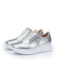 Sneakers metallici argento con finitura testurizzata, dotati di lacci bianchi, cerniera laterale e una suola bianca chunky con un accento rosso.