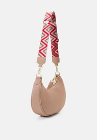 Kompakt handväska i beige med en texturerad yta, med en färgglad zigzag-mönstrad rem och detaljer i guld.