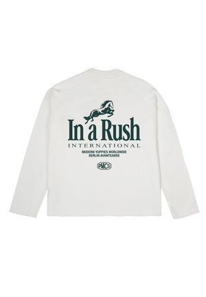 Chemise blanche à manches longues avec un graphisme de cheval vert foncé et les textes "In a Rush INTERNATIONAL", "Modern Yuppies Worldwide" et "Berlin Avantgarde" au dos.
