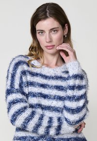 Maglione a righe con texture morbida e pelosa in blu navy e bianco. Design a girocollo con maniche lunghe e dettagli a costine sull'orlo.