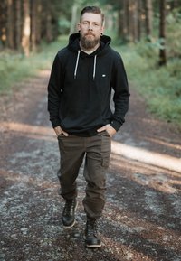 Black hooded sweatshirt with drawstrings, tan cargo pants, and black lace-up boots. Features include a front pocket and solid colors throughout.