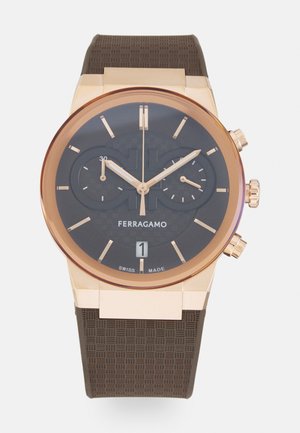 Ferragamo horloge met een ronde zwarte wijzerplaat, accenten van roségoud, een gestructureerde bruine rubberen band en een datumaanduiding op zes uur. Zwitsers gemaakt.