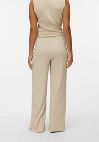 Beige, getextureerde two-piece outfit met een mouwloze top en wijde broek, gemaakt van een zachte, wafelgebreide stof.