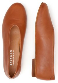 Bailarinas de cuero marrón con punta redondeada y tacón bajo, con detalles recortados en los laterales y una textura suave. Nombre de la marca visible en el interior.