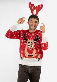 Red holiday sweater featuring a reindeer design, snowflakes, and white accents. Model wears green antlers with red tips, background is plain.