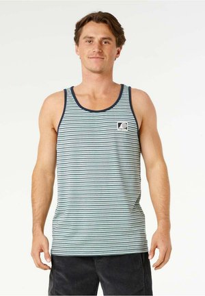 Homme portant un débardeur rayé bleu clair et bleu marine avec un petit logo sur la poitrine, debout devant un fond uni.
