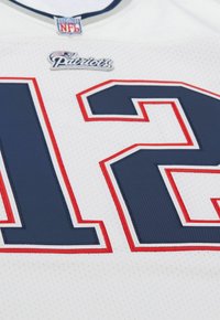 Weißes Sporttrikot mit navyblauen und roten Akzenten. Zeigt das "Patriots"-Logo und die große Nummer "12" mit strukturiertem Stickdetail.