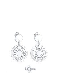 Boucles d'oreilles en argent avec des pendentifs circulaires ornés de motifs de soleil en relief, accompagnées d'une bague assortie au motif de soleil. Surface métallique lisse et réfléchissante.