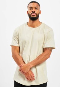 Beige katoenen t-shirt met ronde hals, korte mouwen en een ontspannen pasvorm. Gladde textuur, standaard zoom en minimalistisch ontwerp.