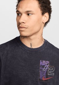 Navy blue cotton t-shirt featuring a graphic print with purple, orange, and white colors, depicting a basketball net and the number 72.