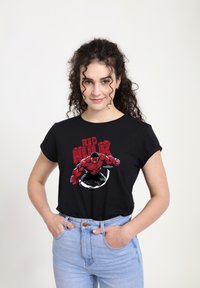 Černé tričko s červenou a černou grafikou postavy Red Hulk, s kulatým designem a ohrnutými rukávy.