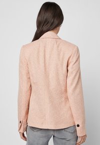 Pfirsichfarbener Blazer mit standardmäßigem Kragen, Ein-Knopf-Manschetten und taillierter Passform, mit vertikalen Linien und glatter Oberfläche.
