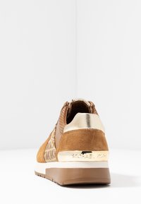 Sneaker in suede marrone con accenti metallici dorati, dettagli forati e suola testurizzata. Presenta il logo sul tallone.