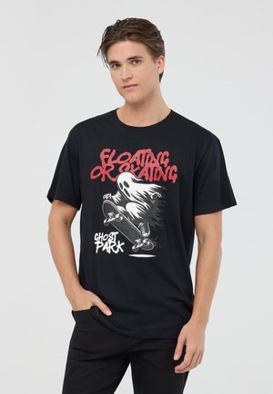 T-shirt nera in cotone con una grafica di un fantasma su uno skateboard con il testo "FLOATING OR SKATING" in rosso sopra e "GHOST PARK" sotto.