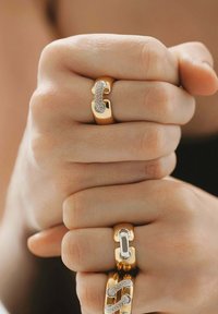 Anillos de oro con un acabado mate suave, que presentan un diseño con diamantes y eslabones en varias formas. Los acentos texturizados añaden contraste.