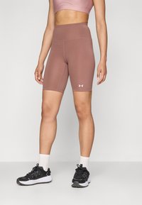 Mid-rise, fitted bike shorts in dusty rose, made from stretchy fabric, featuring flatlock seams and an Under Armour logo on the left hem.