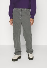 Grey denim jeans with a relaxed fit, featuring a classic five-pocket design, belt loops, and a subtle faded texture. Paired with off-white shoes.