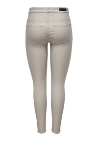 Beige slim-fit broek met twee achterzakken, lussen voor een riem en een zwart merkembleem op de tailleband, getoond van achteren op een witte achtergrond.