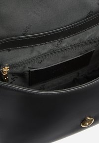 Interno di borsa in pelle nera con tasca con cerniera e motivo con logo del marchio sulla fodera; trama liscia con chiusura a zip dorata.