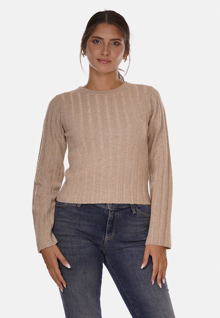 Maglione beige a costine con maniche lunghe e scollatura rotonda, realizzato in un tessuto testurizzato. Indossato con jeans scuri, caratterizzati da un design aderente.