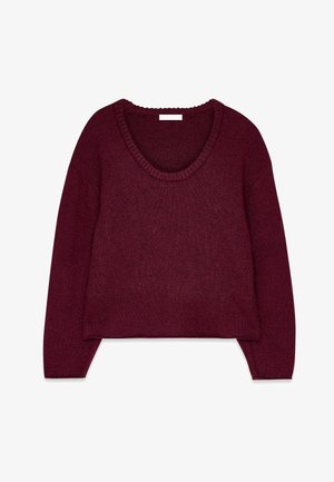 Burgundi spalvos megztinis su V formos iškirpte, ilgomis rankovėmis ir banguota apykakle. Minkšta tekstūra ir atsipalaidavęs siluetas, turintis trumpą hemą.