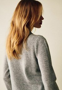 Ljusgrå, långärmad tröja med mjuk textur, figursydd design och rund halsringning, bärs av en person som ses bakifrån.
