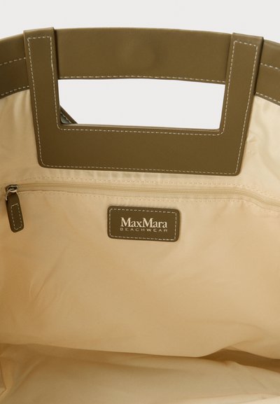 Εσωτερικό μπεζ τσάντας tote με ορθογώνιες λαβές κοψίματος σε ελαιώδες πράσινο, μια τσέπη με φερμουάρ και ετικέτα Max Mara Beachwear.