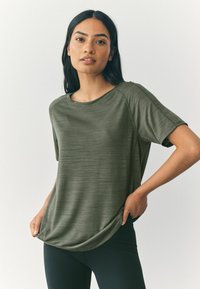 Oliwkowy, sportowy T-shirt wykonany z teksturowanej tkaniny, z okrągłym dekoltem, krótkimi rękawami i luźnym krojem.