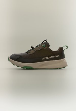 Pojedynczy brązowo-czarny sneaker z zielonymi i beżowymi detalami, widok z boku, logo "The North Face" na pięcie, gruba podeszwa, jednolite jasne tło.