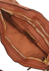 Interno in pelle tan di una borsa con zip dorate, caratterizzato da una texture liscia e un'etichetta singola. La fodera è marrone chiaro con un motivo sottile.