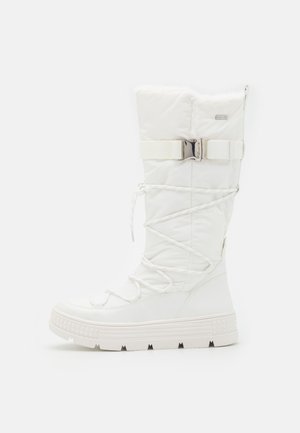 Tall white winter boot with thick sole, laces crisscrossing front, and adjustable strap with metal buckle near the top.
