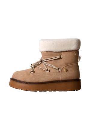 Botte d'hiver en daim beige avec un revers en fourrure blanche, lacets beige passant dans des œillets en métal et semelle épaisse marron.